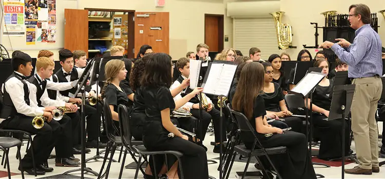 Students rehearsing with their band director in a school music room